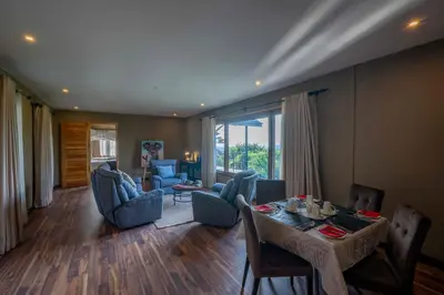 a living room with a table and blue chairs at Ngorongoro Lion's Paw in Ngorongoro