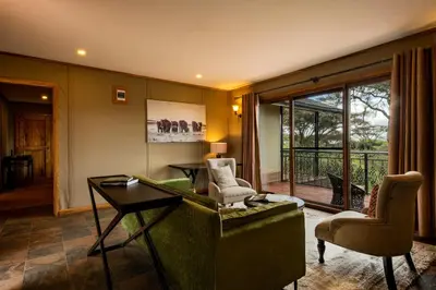 a living room with a green couch and chairs at Ngorongoro Lion's Paw in Ngorongoro