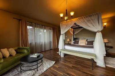 a bedroom with a canopy bed and a couch at Ngorongoro Lion's Paw in Ngorongoro