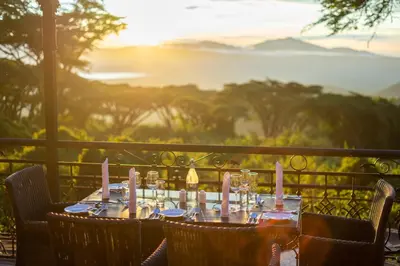 a table with wine glasses sitting on top of a balcony at Ngorongoro Lion's Paw in Ngorongoro