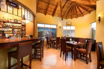 a restaurant with tables and chairs and a bar at Mrimba Palm Hotel in Arusha