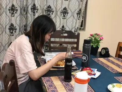 a woman sitting at a table with a plate of food at Wakawaka Hostel Arusha in Arusha