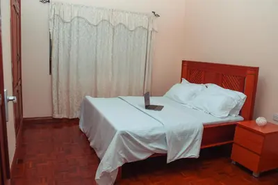 a bedroom with a bed with white sheets and a window at Wakawaka Hostel Arusha in Arusha