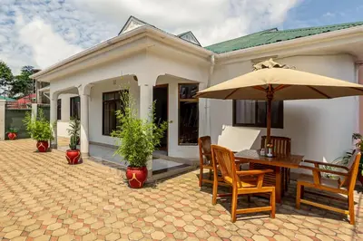 a patio with a table and chairs and an umbrella at Mama Wilsen House in Arusha