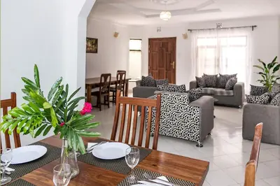 a dining room and living room with a table and chairs at Mama Wilsen House in Arusha