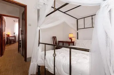 a bedroom with a canopy bed with a table and a chair at Mama Wilsen House in Arusha