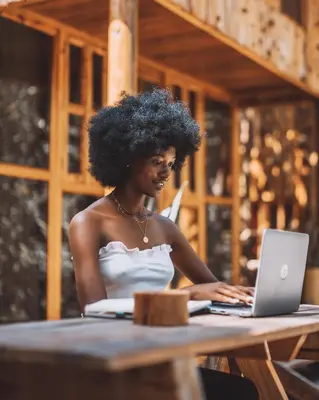 a woman sitting at a table with a laptop at Banana Farm Eco Hostel in Arusha