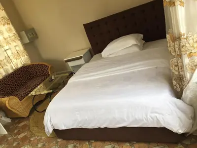 a bedroom with a white bed and a chair at Asmorein Hotel in Babati