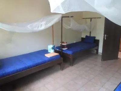 two blue beds in a room with white curtains at Climbers Home in Moshi