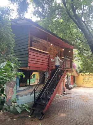 a man standing on the stairs of a tiny house at IBRAHIM Garden Hostel in Arusha