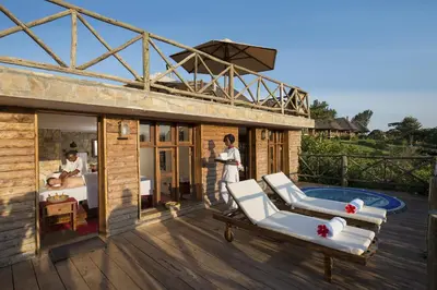 a woman standing on a deck next to a house at Neptune Ngorongoro Luxury Lodge - All Inclusive in Ngorongoro