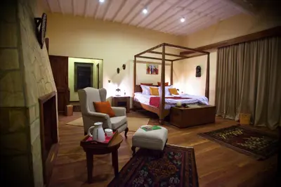 a bedroom with a bed and a chair in a room at Neptune Ngorongoro Luxury Lodge - All Inclusive in Ngorongoro
