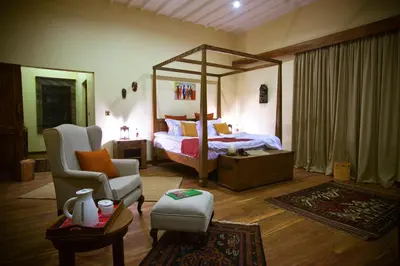 a bedroom with a canopy bed and a chair at Neptune Ngorongoro Luxury Lodge - All Inclusive in Ngorongoro