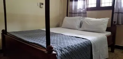 a bedroom with a bed with white sheets and pillows at Aivlys Lodge Kilimanjaro in Msaranga