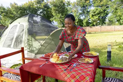 a woman sitting at a table with a plate of food at Aivlys Lodge Kilimanjaro in Msaranga