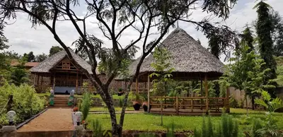 a large wooden house with a thatched roof at Aivlys Lodge Kilimanjaro in Msaranga