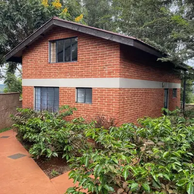 a red brick house with bushes in front of it at Lilac Hideaway in Karatu