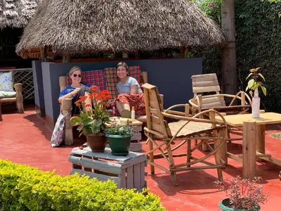 two women sitting on a porch with chairs and a hut at The Better Inn in Moshi