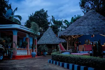 a house with two thatched umbrellas and chairs at The Better Inn in Moshi
