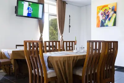 a dining room with a table with chairs and a television at Two Mountains Lodge in Arusha