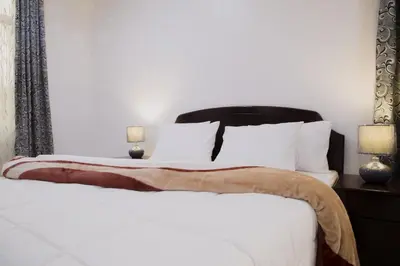 a bedroom with a white bed with a black headboard at Two Mountains Lodge in Arusha