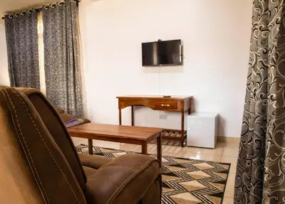 a living room with a chair and a table and a television at Two Mountains Lodge in Arusha