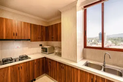 a kitchen with wooden cabinets and a sink and a window at Kibo Palace Apartments in Arusha