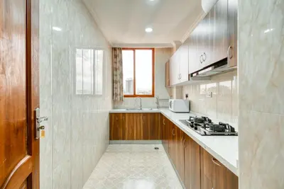 a large kitchen with wooden cabinets and a window at Kibo Palace Apartments in Arusha