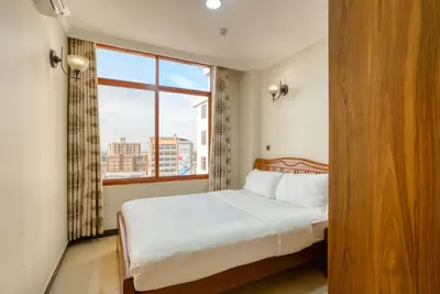 a bedroom with a bed and a large window at Kibo Palace Apartments in Arusha