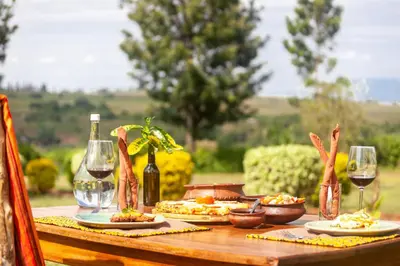 a table with two plates of food and wine glasses at Karatu Tented Lodge in Karatu