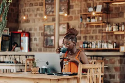 a woman sitting at a table with a cup of coffee and a laptop at Chanya by Ardhi Africa in Moshi
