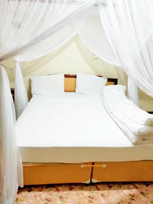 a bed with white sheets and white curtains at Kilimanjaro Star Hotel in Moshi