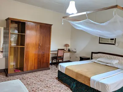 a bedroom with a bed and a cabinet and a desk at Kilimanjaro Star Hotel in Moshi