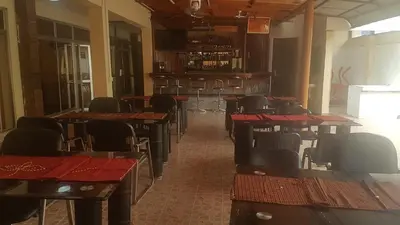 a restaurant with tables and chairs and a bar at Kilimanjaro Star Hotel in Moshi