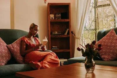 a woman sitting on a couch holding a piece of paper at Mambo Hideaway in Arusha