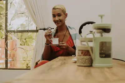 a woman sitting at a table holding a cup at Mambo Hideaway in Arusha