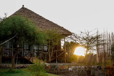a house with the sunset in the background at Kutoka Lodge in Arusha