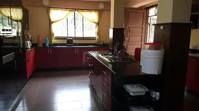 a kitchen with red cabinets and a stove top oven at Kilimanjaro Country House in Moshi