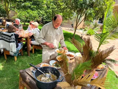 an older man preparing a buffet of food on a table at Haradali's Home in Arusha
