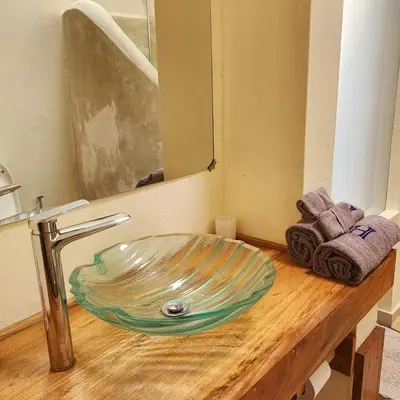 a bathroom sink with a glass bowl on a wooden counter at Haradali's Home in Arusha