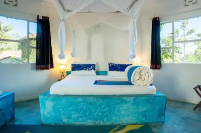 a bedroom with a large bed in a room with windows at Dan Stam Hotel in Arusha