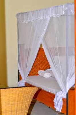 a bed with a canopy with white sheets and towels at New Favour Lodge in Arusha