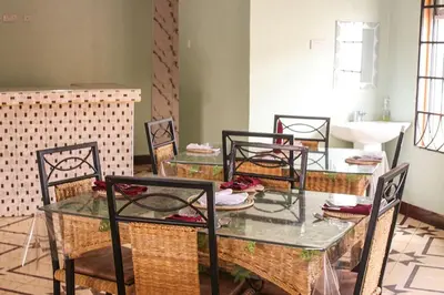 a dining room with a glass table and chairs at New Favour Lodge in Arusha