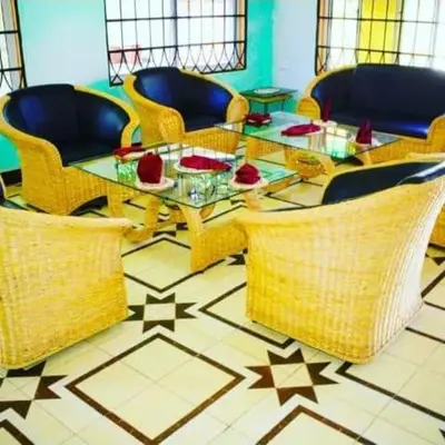 a living room with a glass table and wicker chairs at New Favour Lodge in Arusha