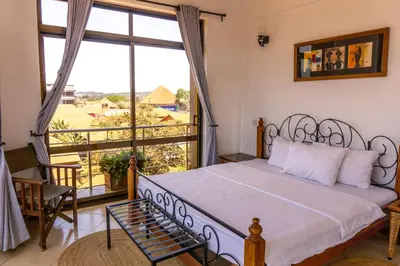 a bedroom with a bed and a large window at Lilac Elevate Inn in Karatu