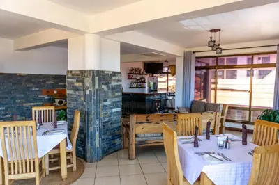 a restaurant with tables and chairs and a fireplace at Lilac Elevate Inn in Karatu
