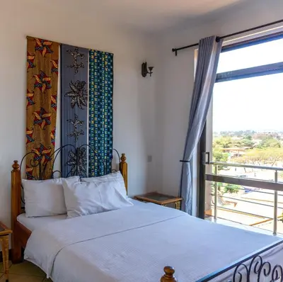 a bedroom with a bed and a large window at Lilac Elevate Inn in Karatu