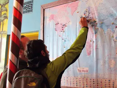 a man is painting a map on a wall at First Point Arusha Hostel in Arusha
