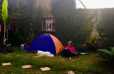 a girl sitting next to a tent in the rain with a dog at First Point Arusha Hostel in Arusha