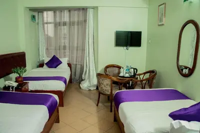 a room with two beds and a table with a mirror at New Hotel Aquiline in Arusha